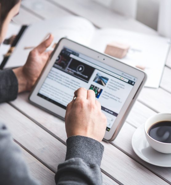 man-sitting-at-table-with-coffee-cup-using-digital-tablet